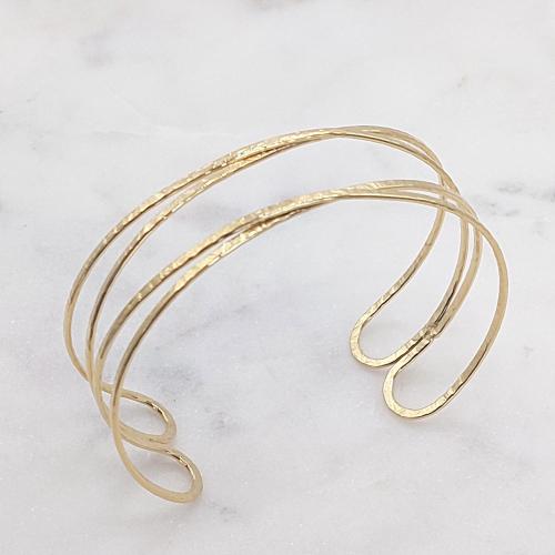 Bracelet en acier inoxydable doré fin et flexible, composé de bandes élégantes qui s'enlacent autour du poignet pour un charme subtil.